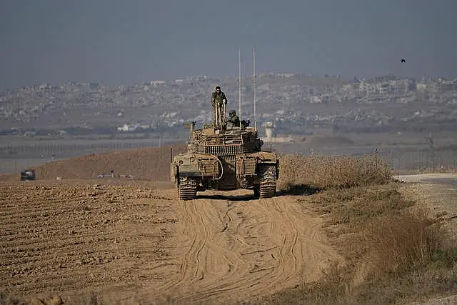 Israeli Defence Forces soldiers work on their tank near the Israel-Gaza border, as seen from southern Israel