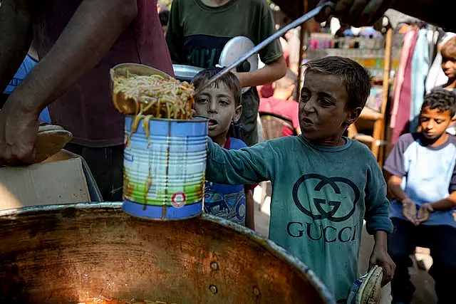 A displaced child lines up for food distribution in Deir al-Balah, Gaza Strip