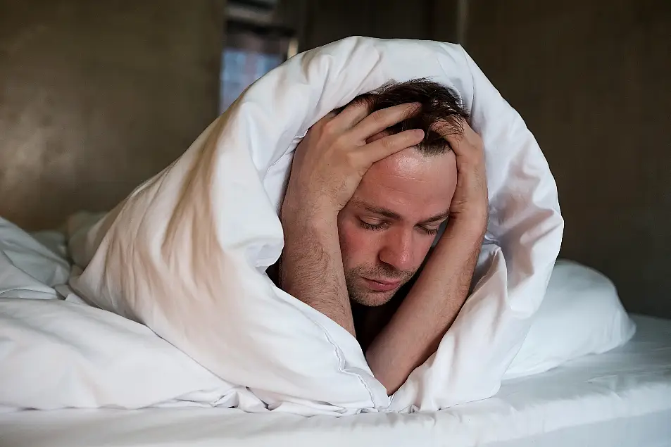 Stressed man laying awake in bed unable to sleep 