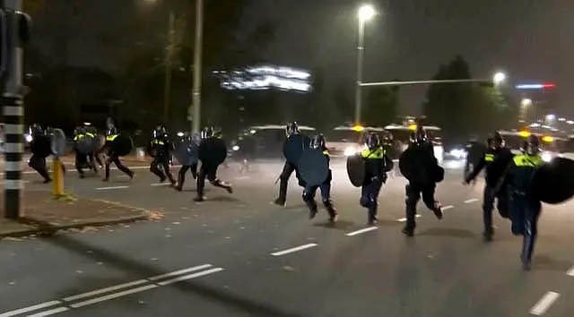 Police in riot gear run towards protesters, after pro-Palestinian supporters marched near the football stadium, in Amsterdam, Netherlands