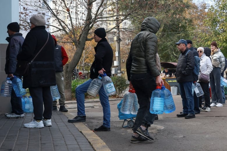 People queue to fill up bottles with drinking water.