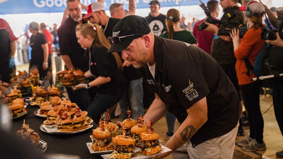 A cook holds a plate of burgers to be judged at the 2023 World Food Championships.