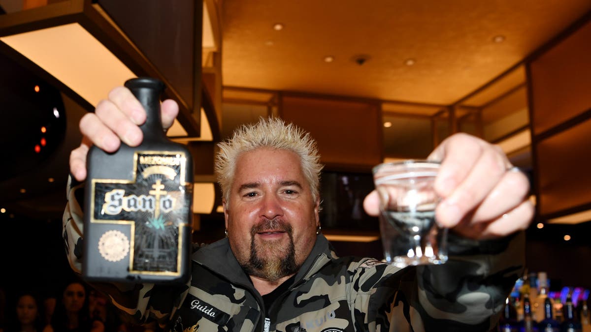 guy fieri holding up bottles of santos